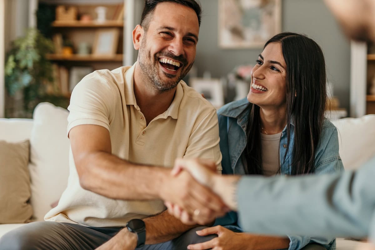 Young couple looks happy while meeting with roofing contractor 