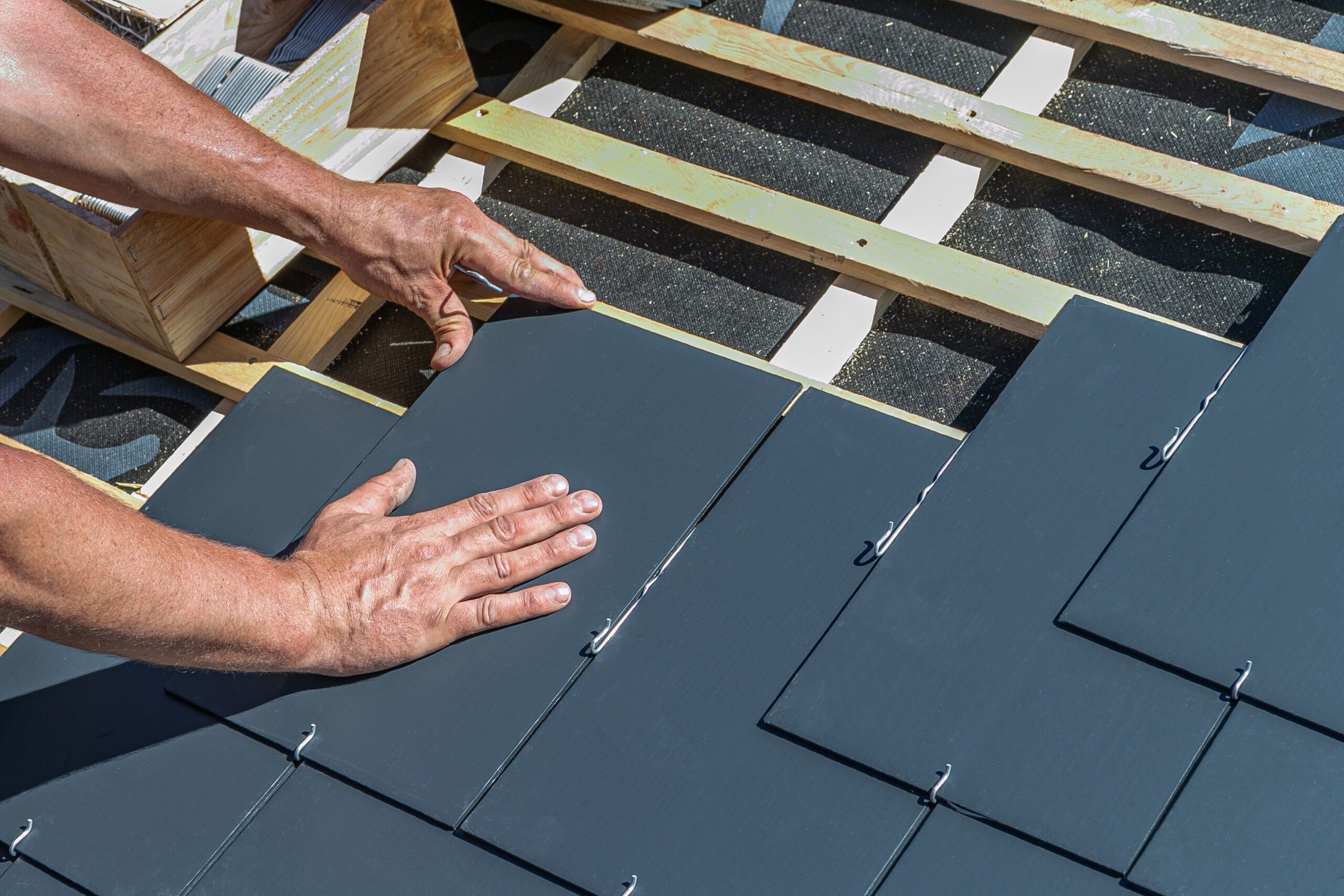 Craftsmen are installing a slate roof home.Professional roof workers installing roof for a old house .Working on rooftop.