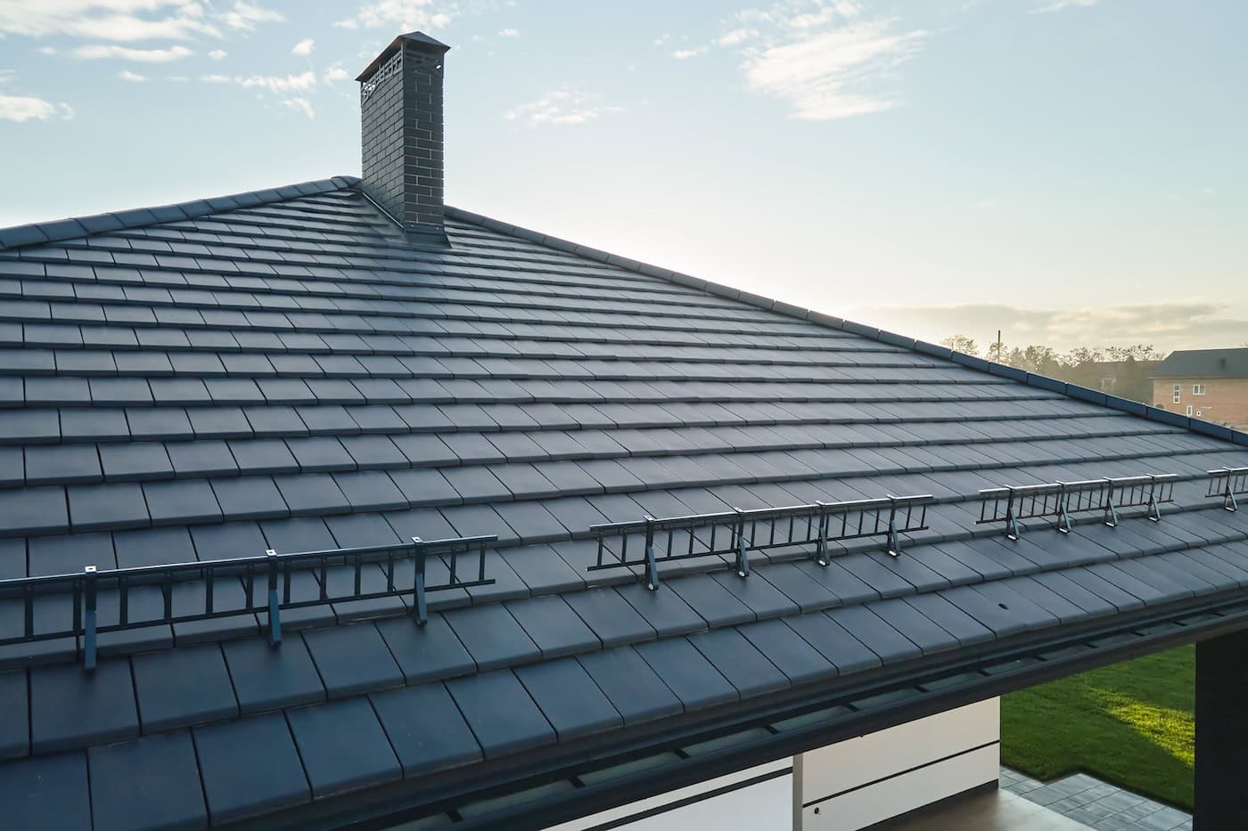 Closeup of house roof top covered with ceramic shingles. Tiled covering of building.