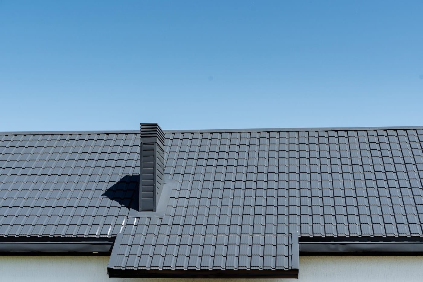 A building with a rectangular shape featuring a chimney on the roof, made of composite materials. The facade is designed with urban engineering, set against a blue sky backdrop