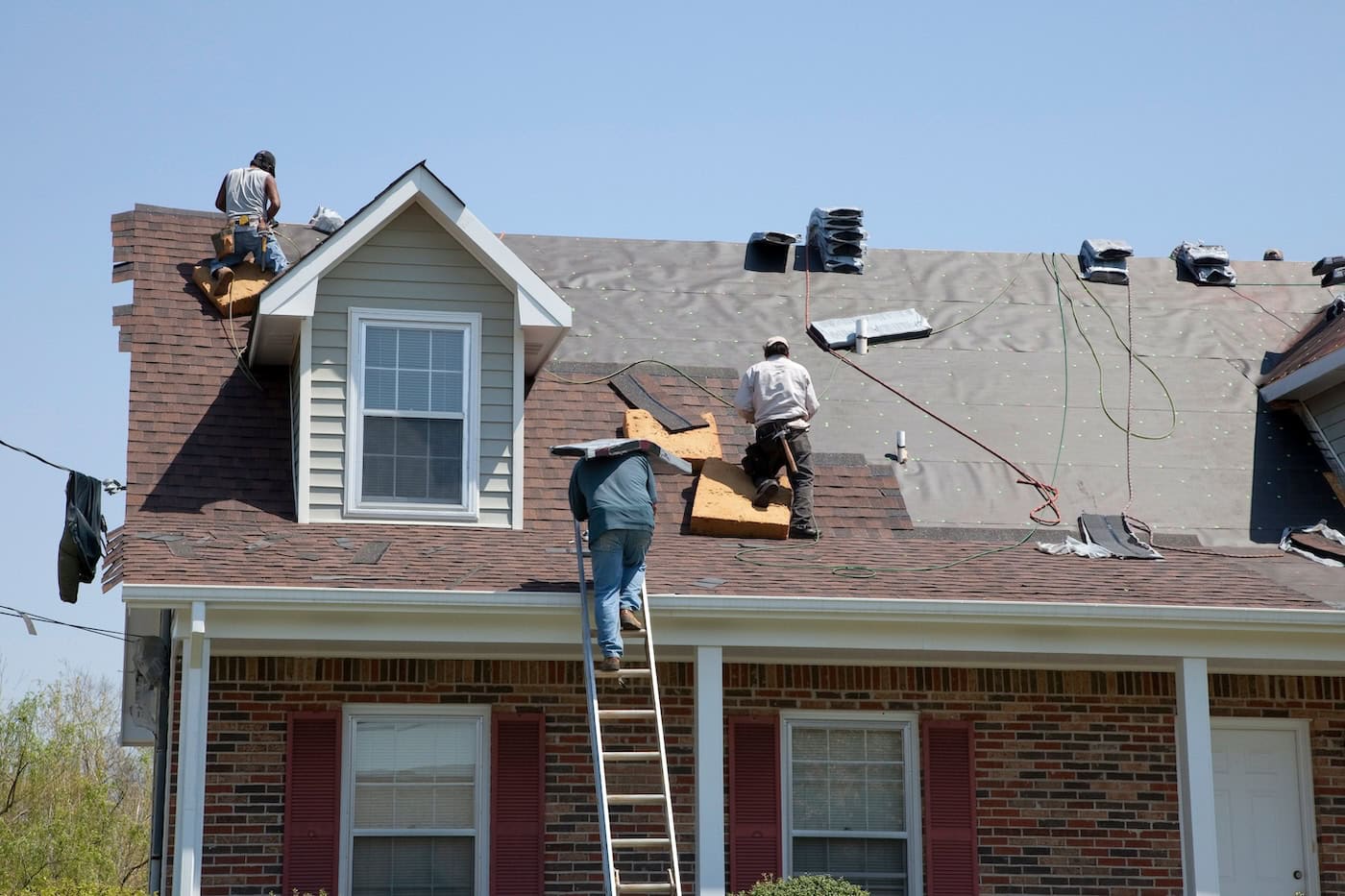 Roofers replacing damaged shingles after storm with very high winds came through over night