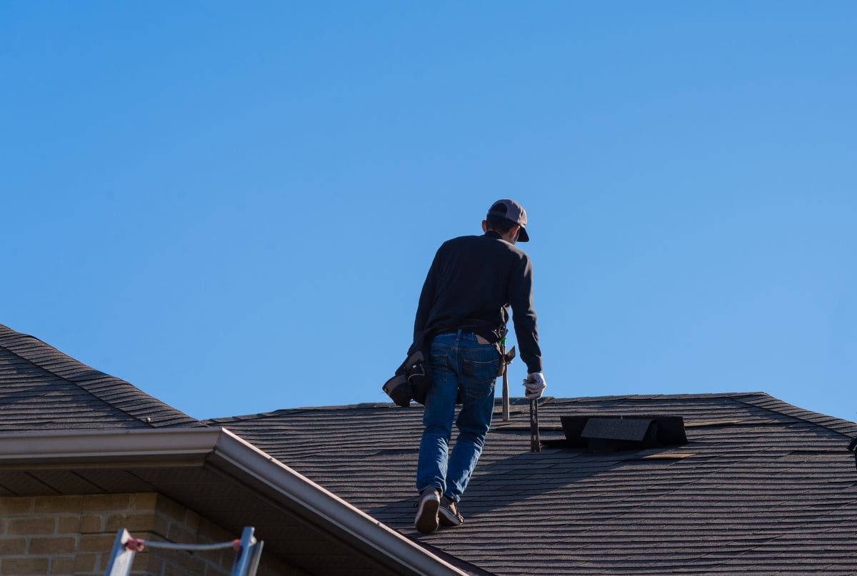 storm damage roof inspection worker on top of house