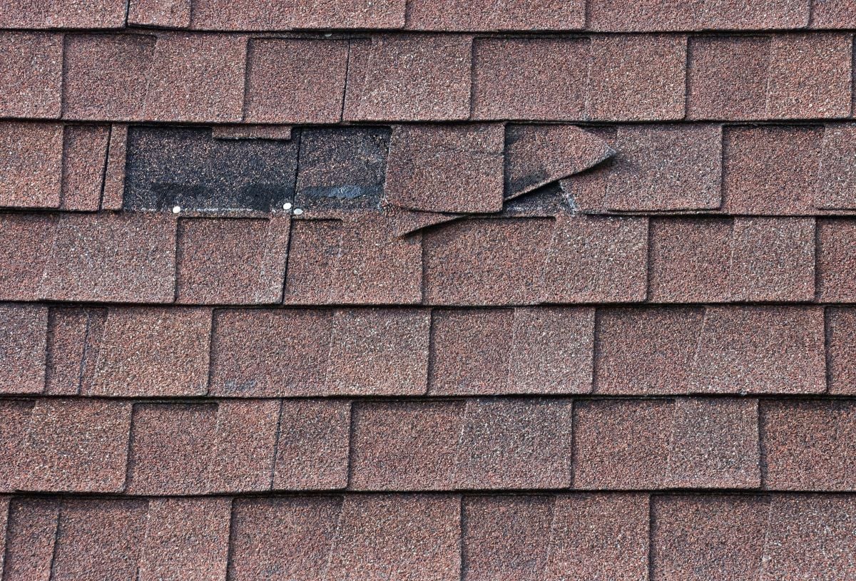 roof wind damage dark brown shingles missing leaving black stains