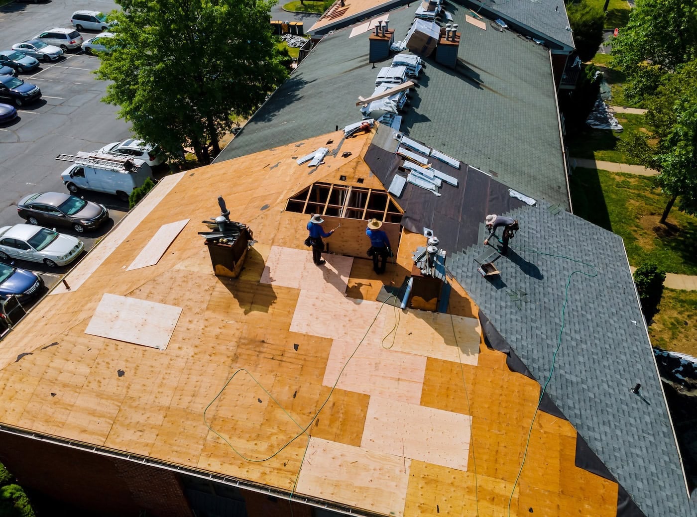 Crew tears off shingles and exposes plywood deck on large commercial roof