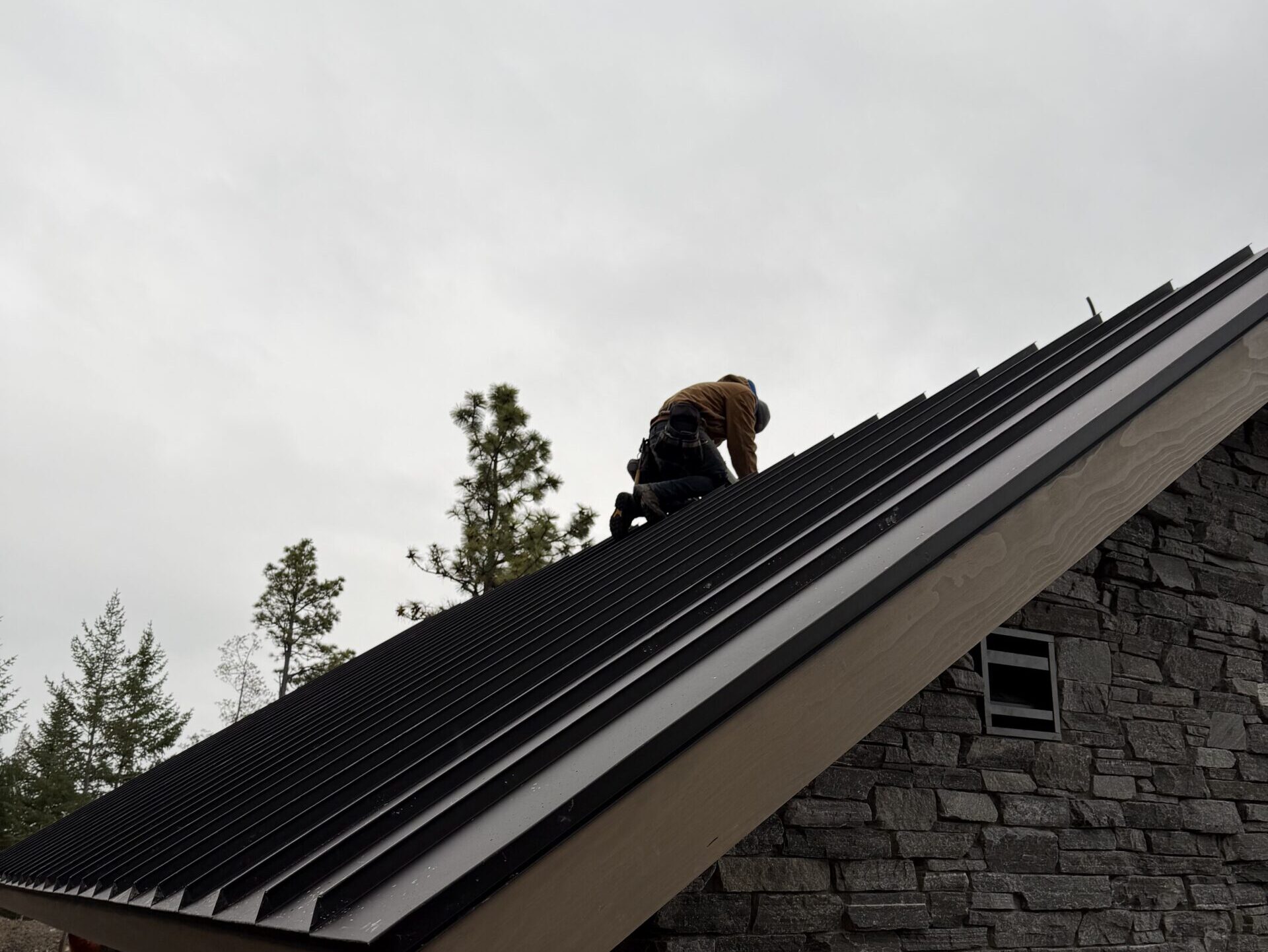 roof leak inspection worker on top of metallic roof
